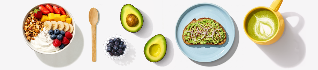 yogurt bowl, wooden spoon, bowl of blue berries, half avocado, avocado toast, matcha tea