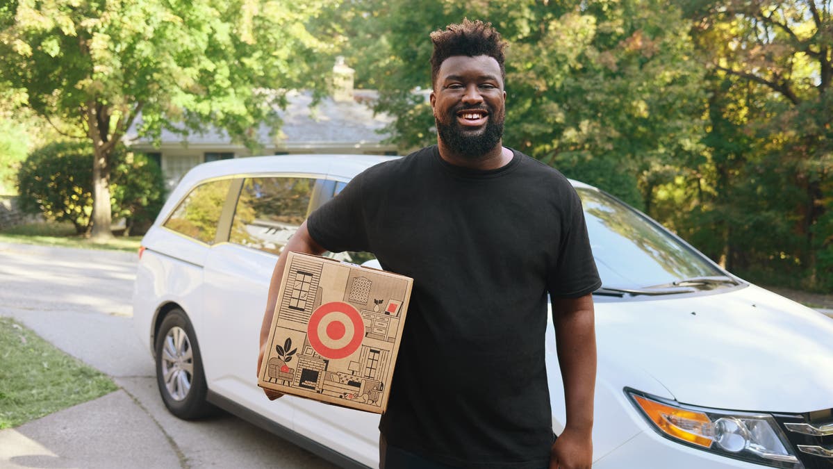 Shipt driver holding a Target box in front of his vehicle
