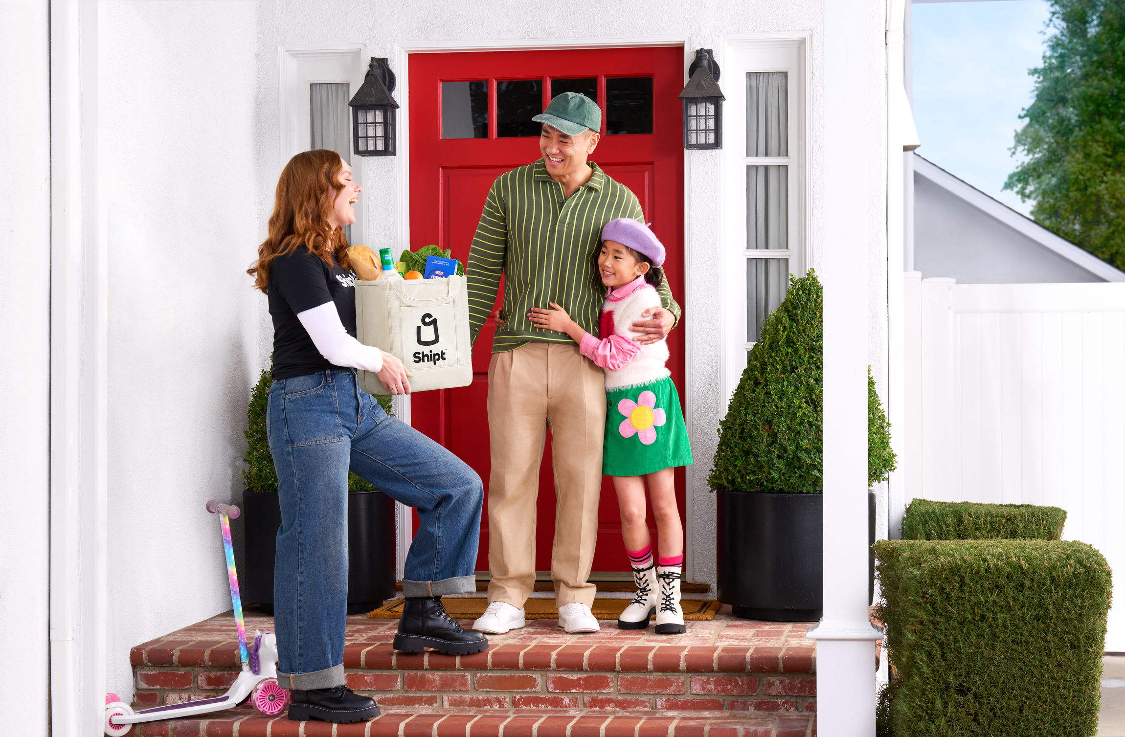 A grocery bag on the mat at a red front door