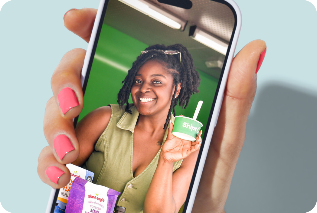 Hand holding a phone showing a photo of a woman with an ice cream sample at an offsite event.