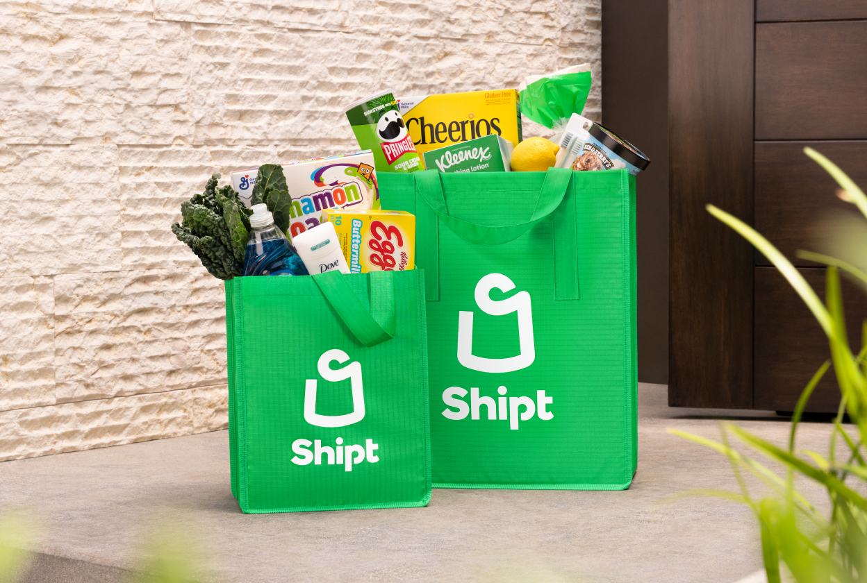 Shipt green shopping bag at door step filled with fresh groceries 