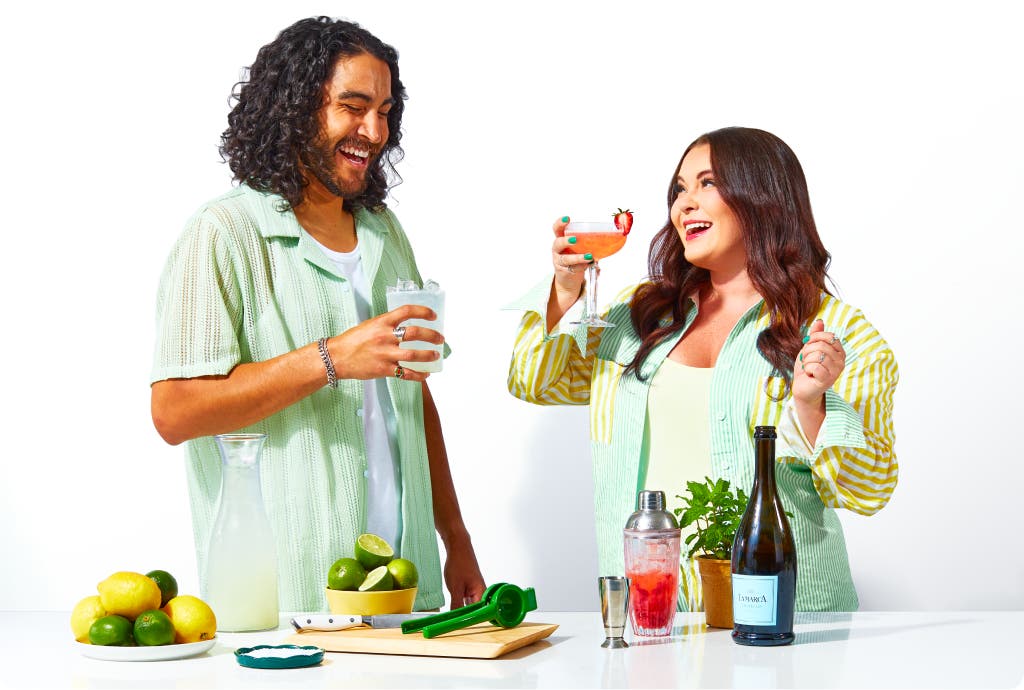 A man and a woman enjoying a drink behind a countertop with garnishes and mixers