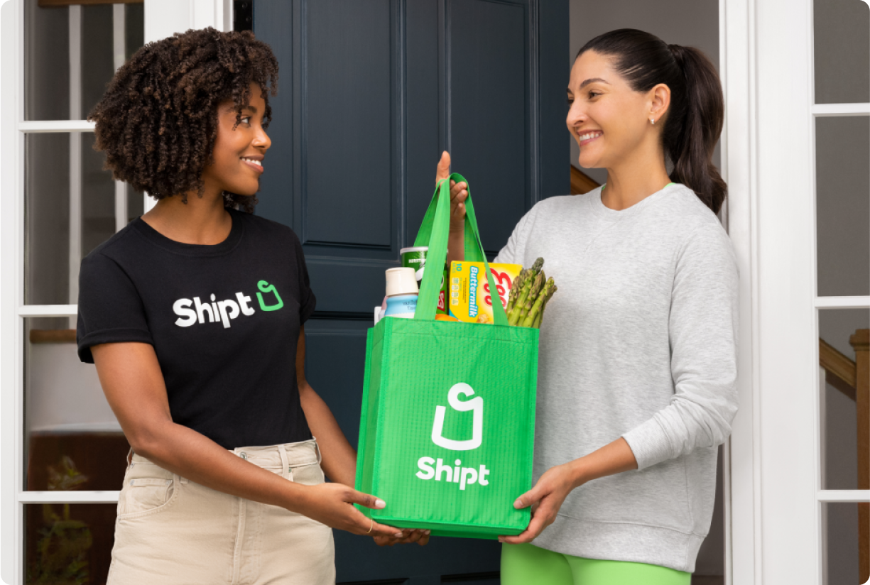 Shopper handing green Shipt bag to customer at front door