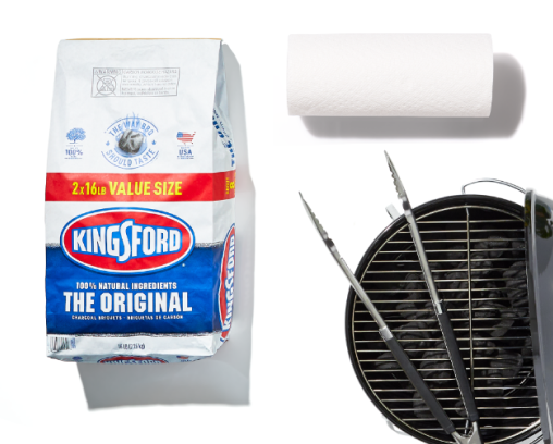 A bag of charcoal, a grill with tongs, and a roll of paper towels
