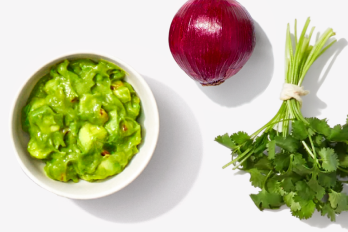 small bowl of guacamole, whole red onion, fresh bunch of cilantro