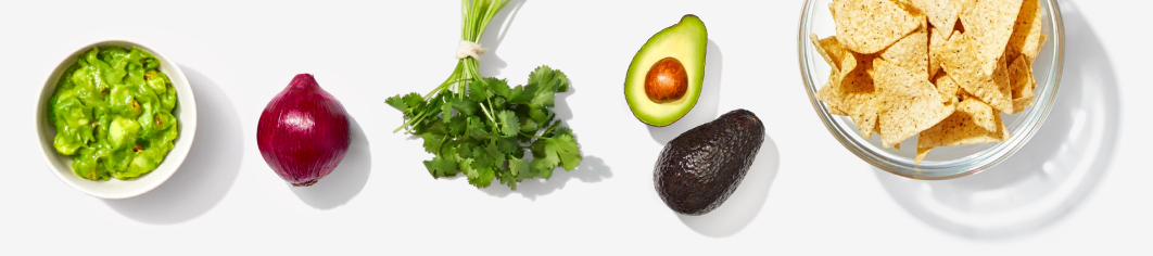 small bowl of guacamole, whole red onion, fresh bunch of cilantro,  avocado, bowl of tortilla chips