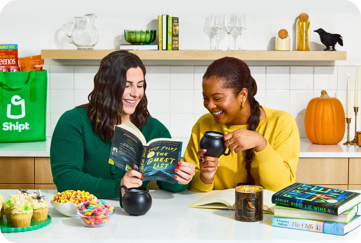 Two woman sharing a book at the kitchen counter with Shipt green bag