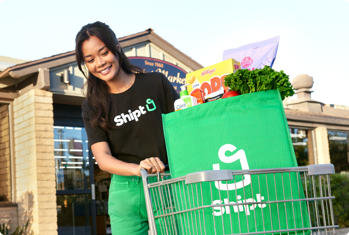 Shopper pushing cart with Shipt grocery bag