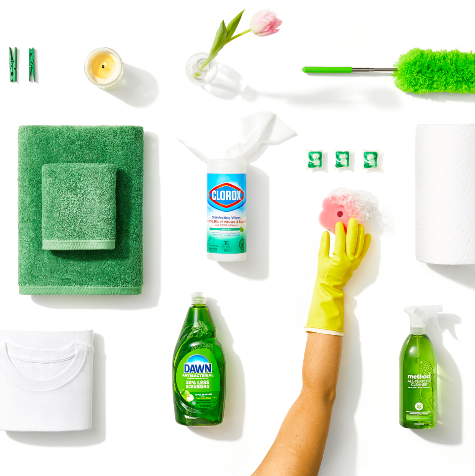 Various green-colored household supplies, like Dawn, Clorox wipes, and Method cleaner, on a white background
