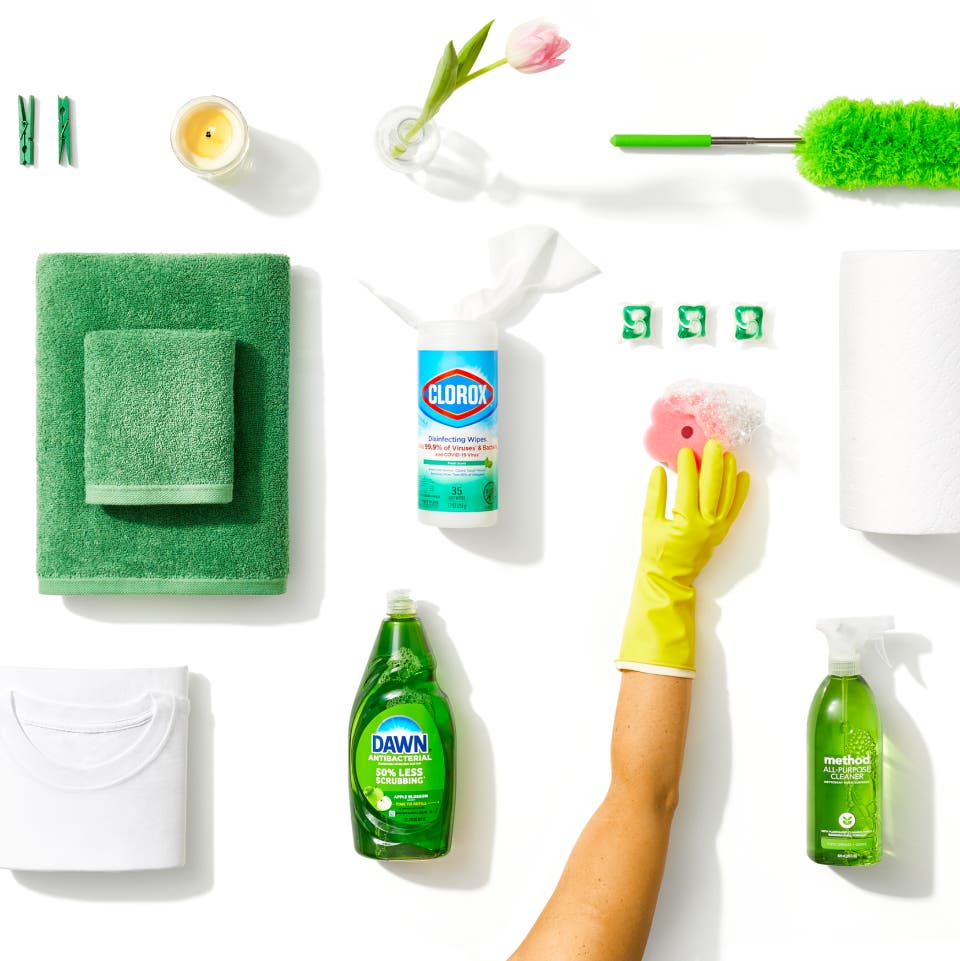 Various green-colored household supplies, like Dawn, Clorox wipes, and Method cleaner, on a white background