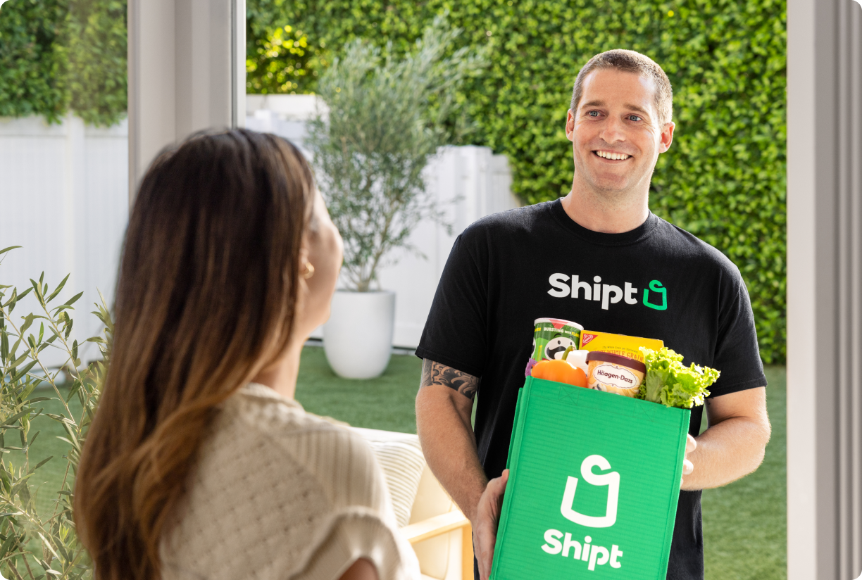 Shopper handing green Shipt bag to customer at doorstep