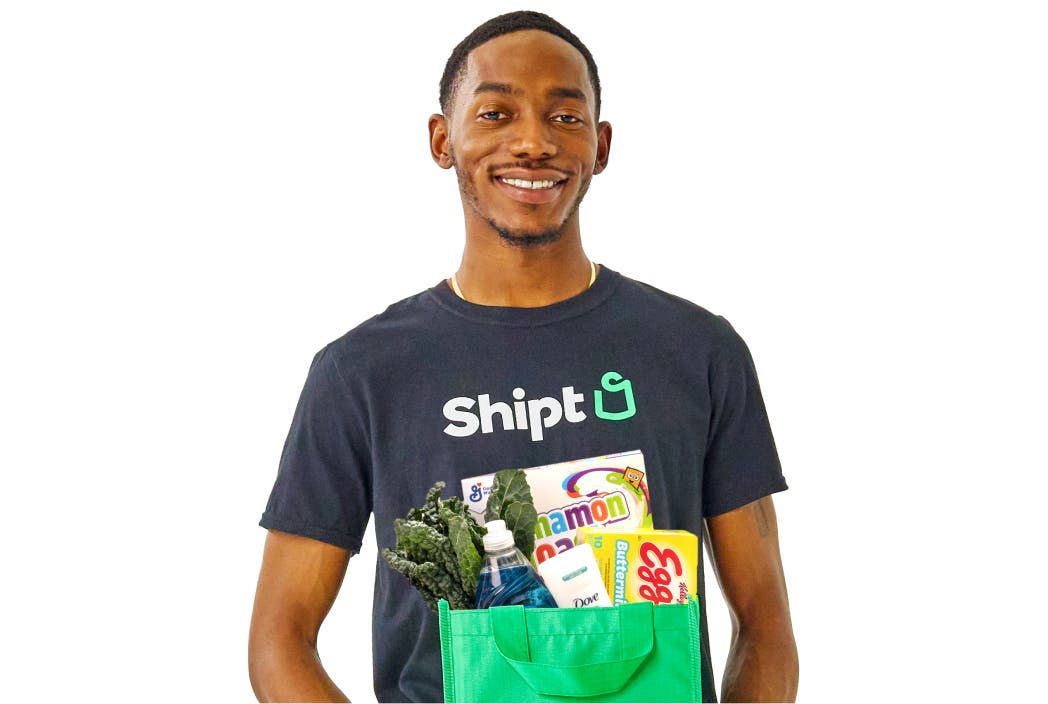 Shopper holding a green Shipt bag fill of items
