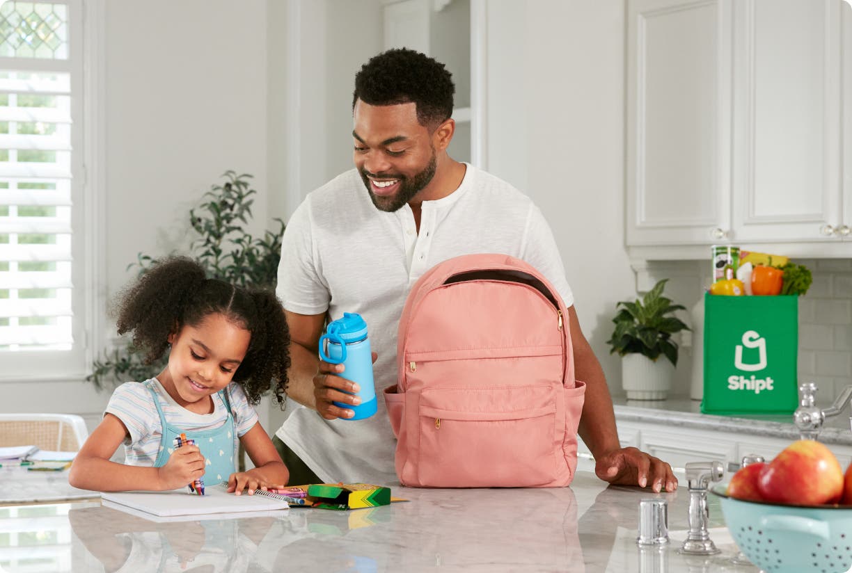 Parent and child at kitchen countertop with Shipt bag
