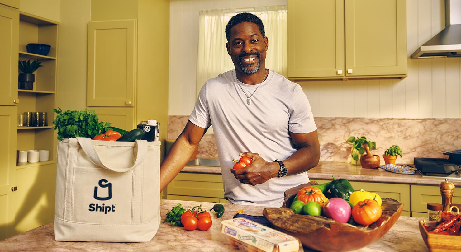 Sterling K. Brown stands with Shipt tote bag and groceries in kitchen