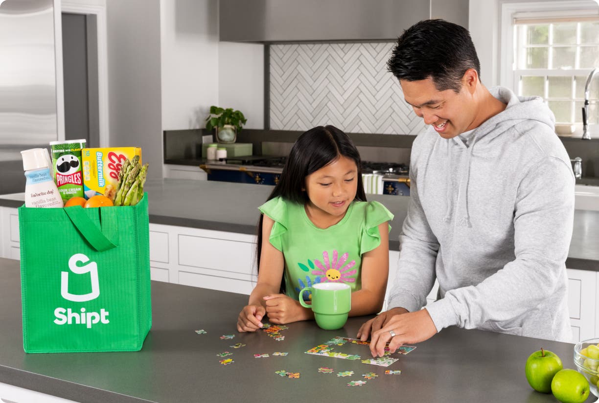 Person and child putting a puzzle together at kitchen counter with Shipt bag