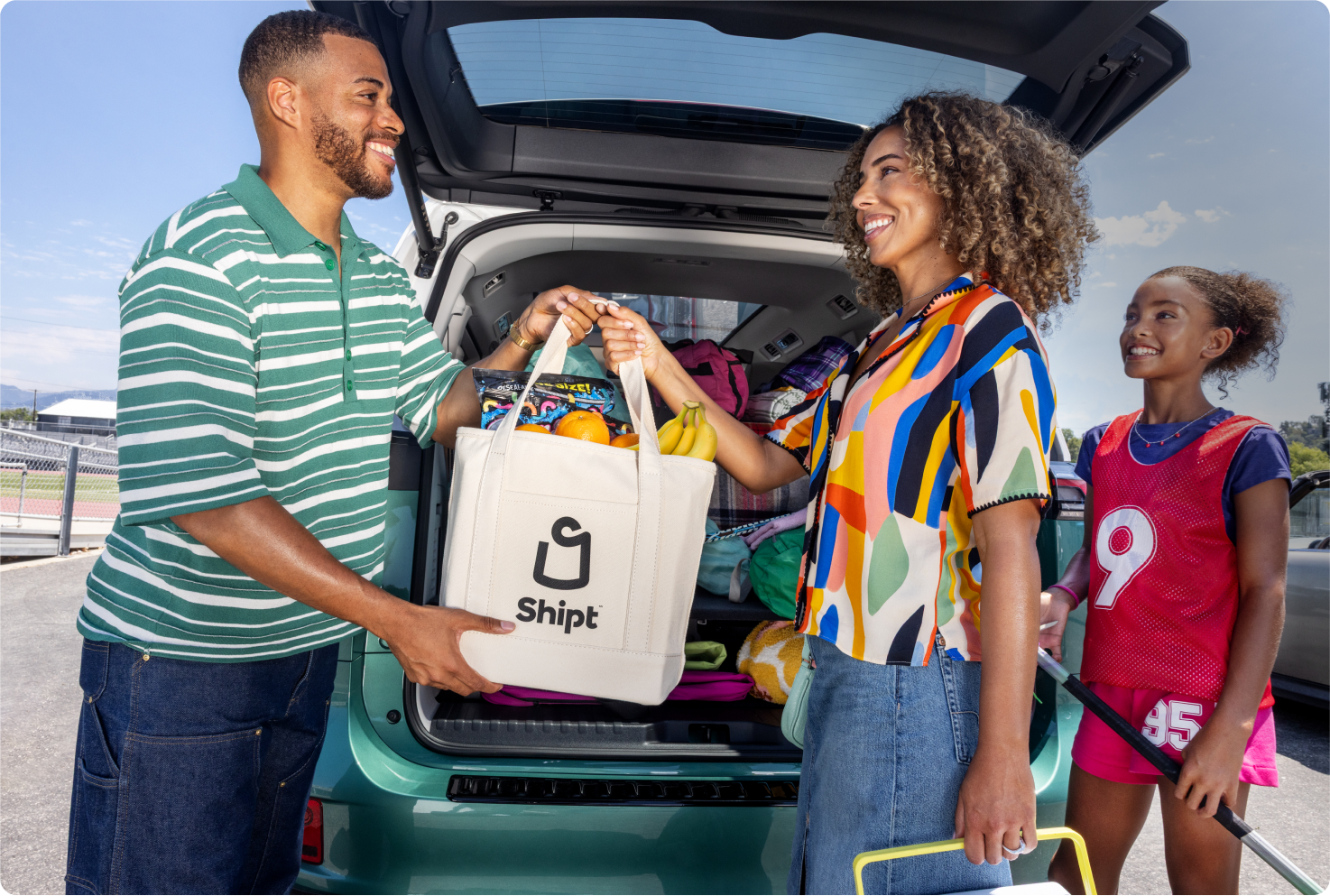 Image of family with white Shipt bag in front of trunk