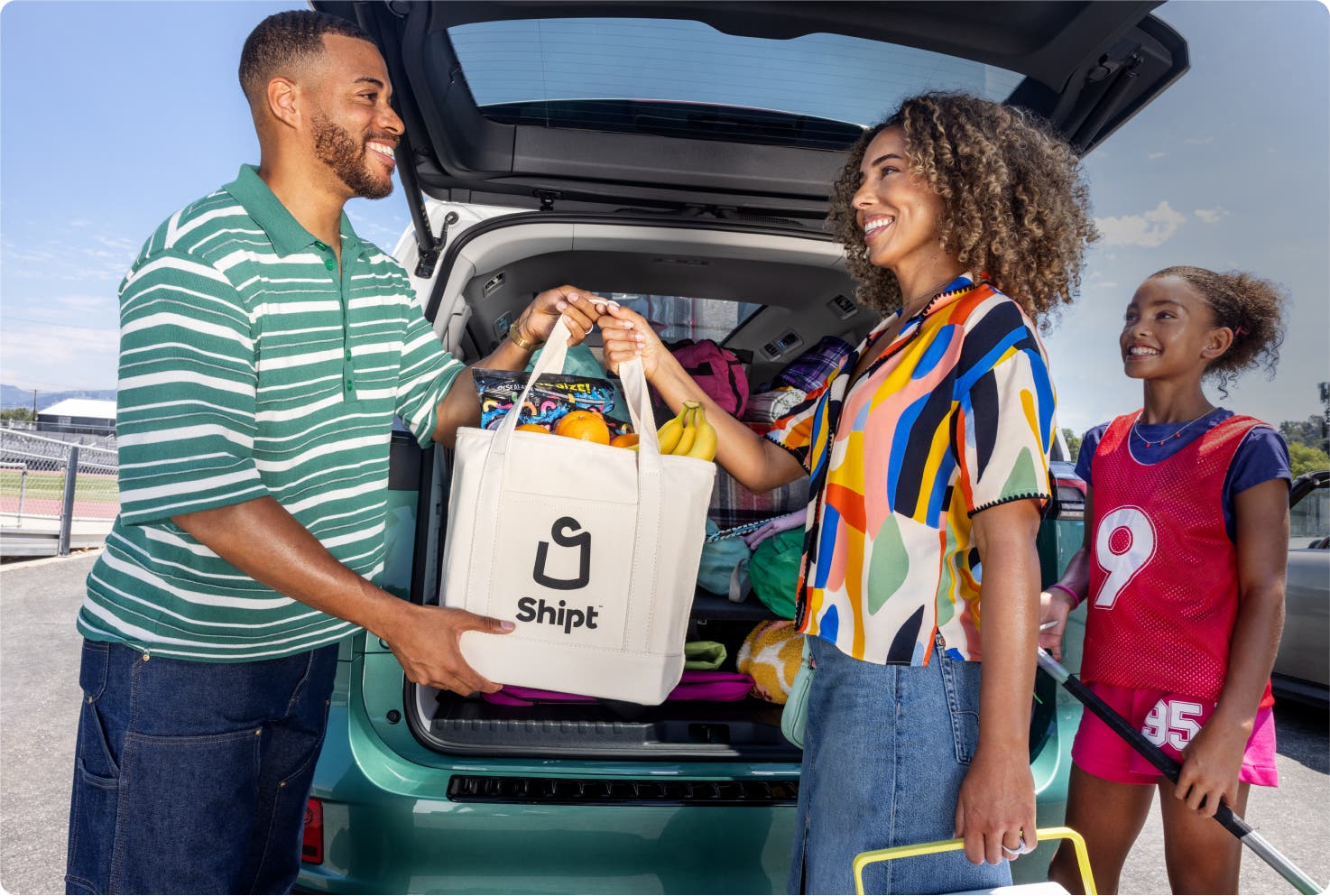 Image of family with white Shipt bag in front of trunk