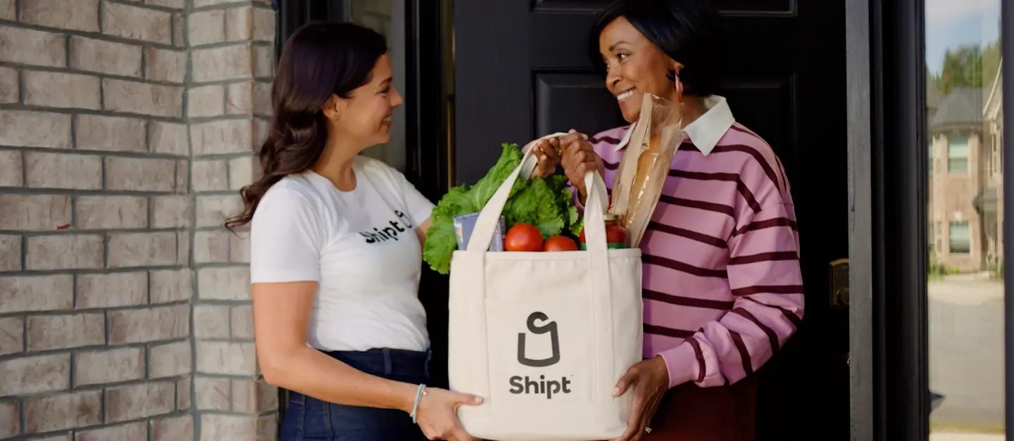 shopper handing off grocery bag to member