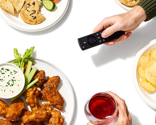 Assorted food and hand holding a tv remote