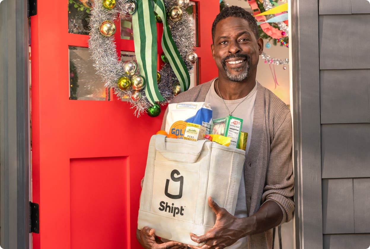 Shopper handing Shipt delivery to Sterling K. Brown at his front door.