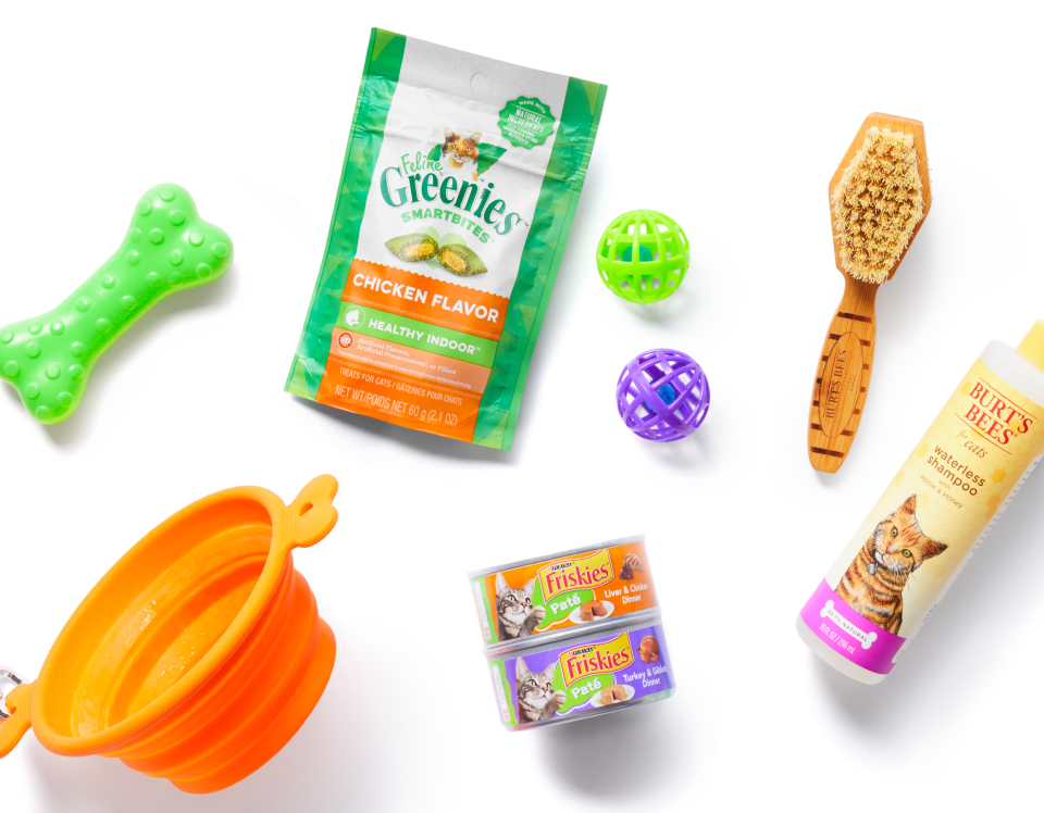 A bag of Shipt groceries filled with pet supplies on a grass lawn, surrounded by pet toys