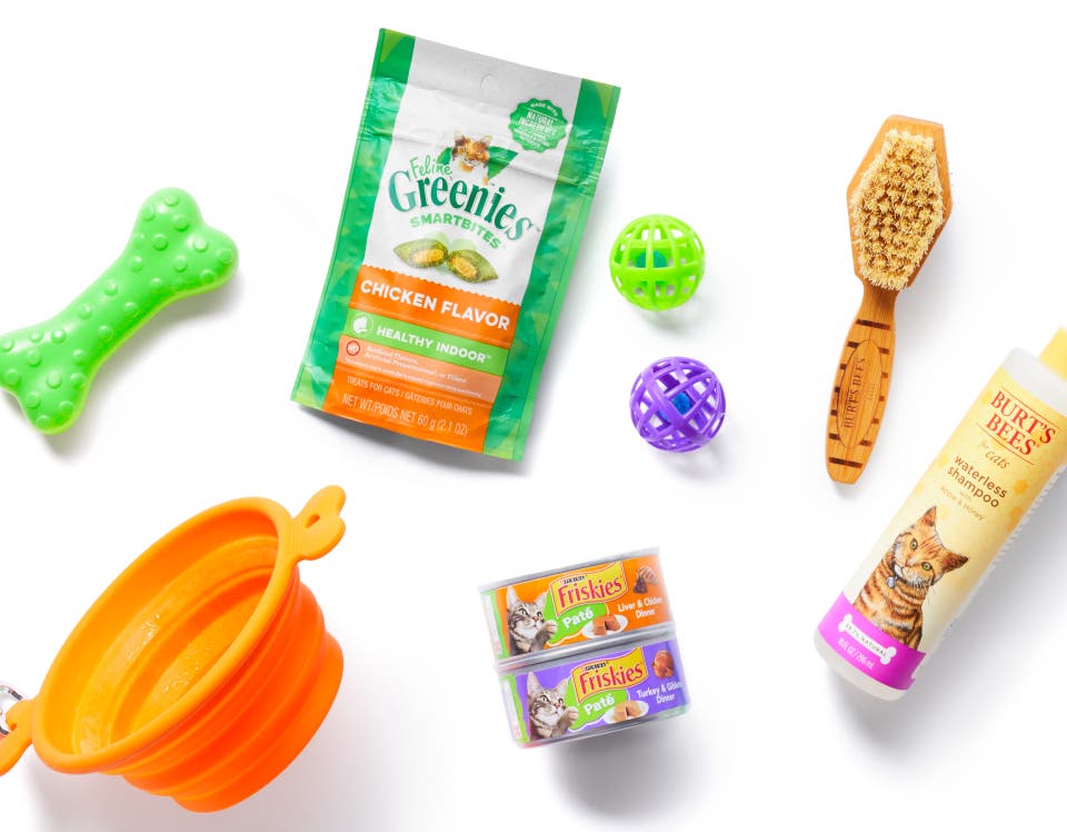 A bag of Shipt groceries filled with pet supplies on a grass lawn, surrounded by pet toys