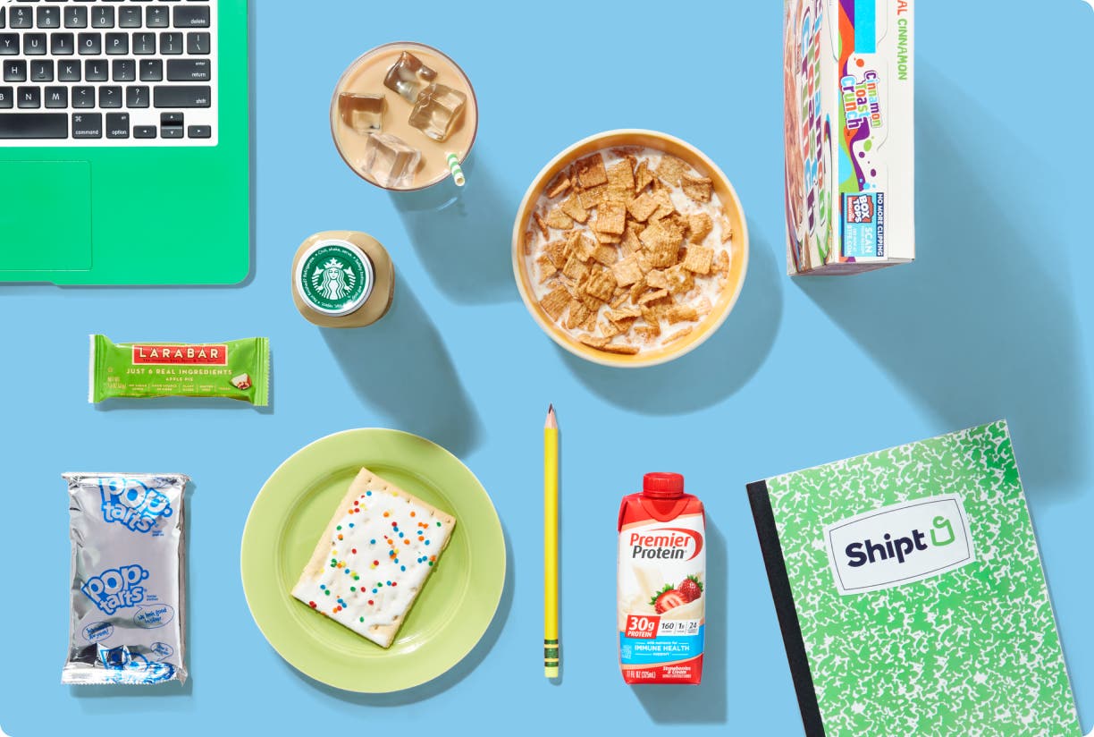 College desk full of snacks, computer, and notebook