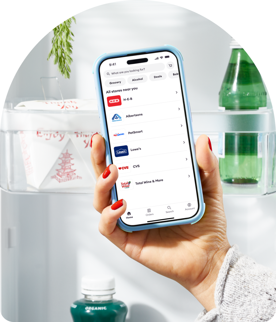 Hand holds a smartphone displaying nearby stores in the Shipt app.