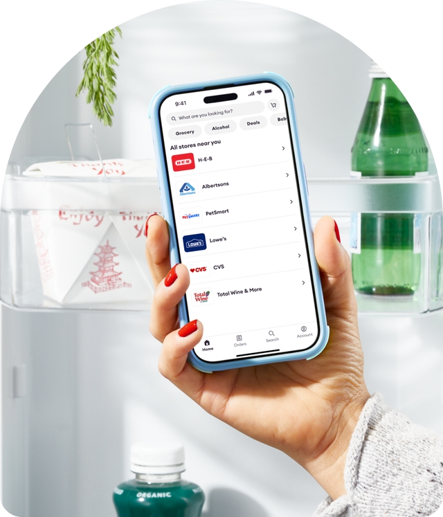 Hand holds a smartphone displaying nearby stores in the Shipt app.